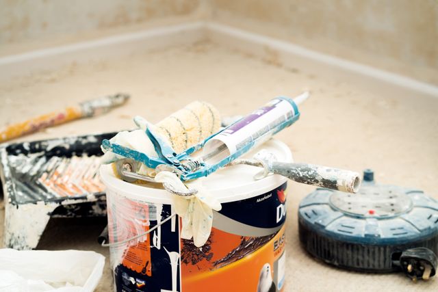 A collection of painting tools and materials for home renovation, featuring paint rollers and a bucket.